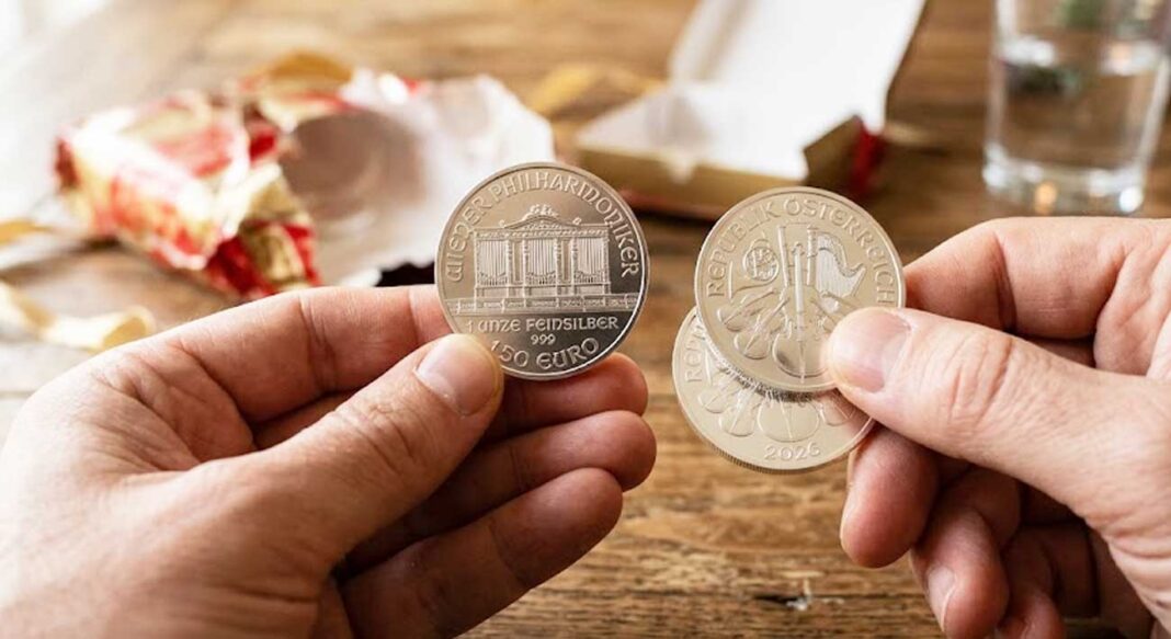 Detailný záber na strieborné investičné mince Viedenská filharmónia (1 oz) v rukách po rozbalení darčeka.