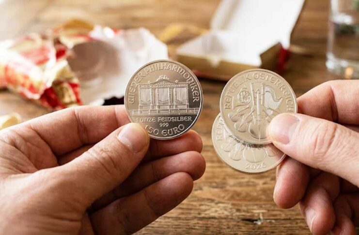 Detailný záber na strieborné investičné mince Viedenská filharmónia (1 oz) v rukách po rozbalení darčeka.